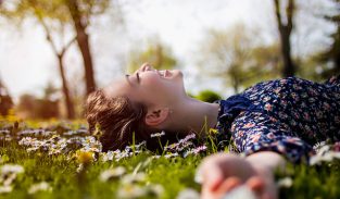 Pretty young teenage girl laying on a grass